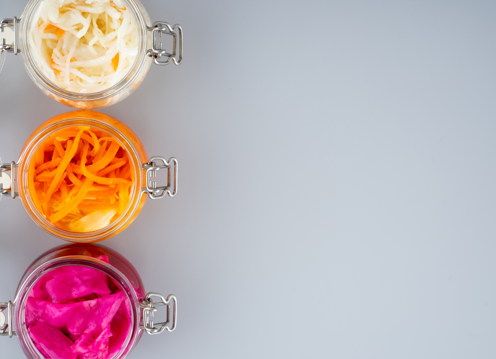 Homemade Village Fermented Sauerkrauts, Red Cabbage and Korean Carrot in Glass Jars, Gray Background. Concept Probiotics Food, Supplement for Gut Health . Adaptogens. Superfood, Top View. Copy Space.
